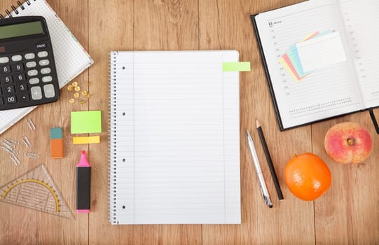a calendar and a notepad lie on a desk with pens and calculator