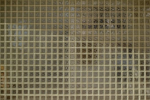 The close-up of a wall of glass tiles with a semi-permeable surface.