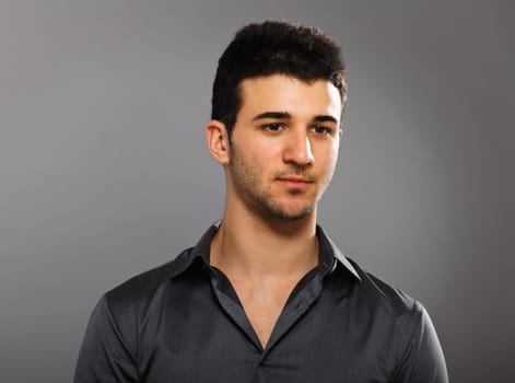 Young businessman portrait isolated on gray background. Looking away from the camera.