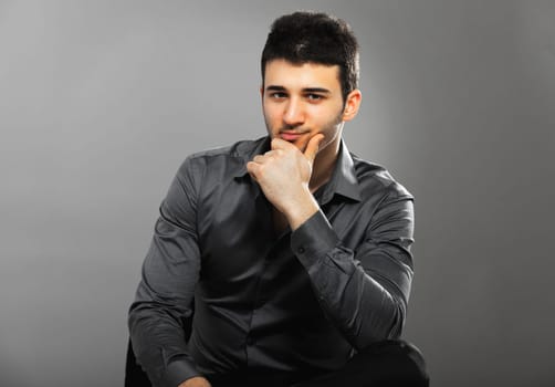 Young businessman thinking. Isolated on gray background