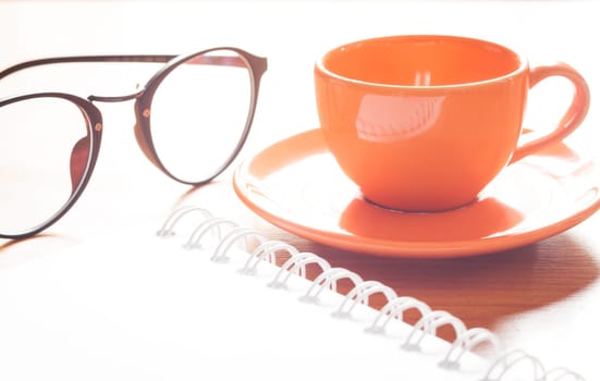 Close up of coffee cup with book and eyeglasses, stock photo