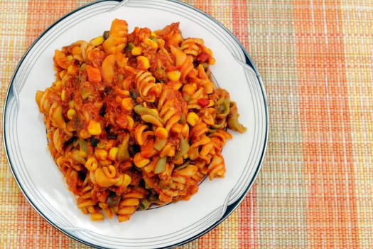Cooked tri-color rotini spiral pasta made with spinach, tomatoes and carrot, mixed with sweet corn, green and red sweet bell pepper, carrots and green beans.