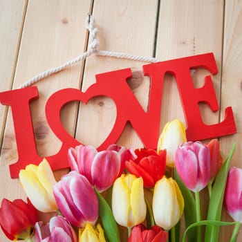 Love on rustic background made of wood with colorful tulips