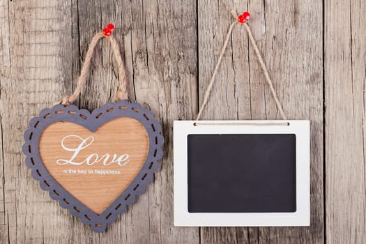 Empty wooden blackboard sign and heart shape frame with love text on wooden background. valentines day card concept.