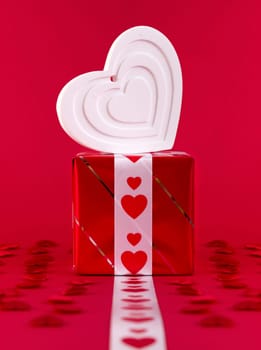 Red Holidays gift and heart on red background. Valentines day background.