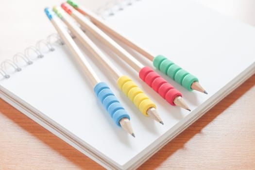 Pencils on open blank white notebook on the desk, stock photo