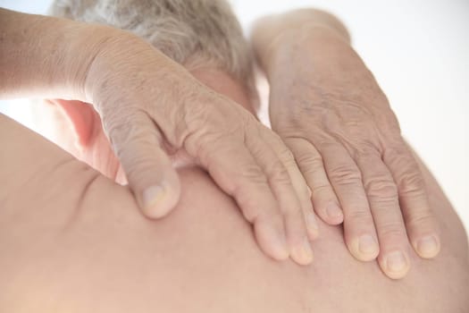 Senior man tries to reach the painful area on his back.