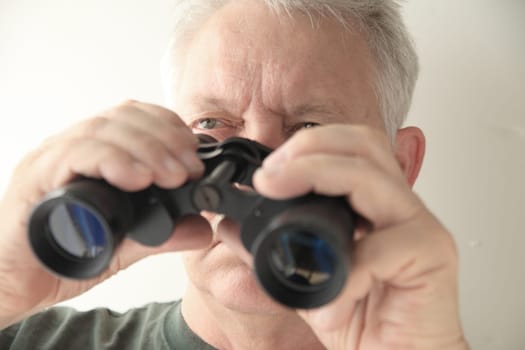 An older man holds an old pair of binoculars