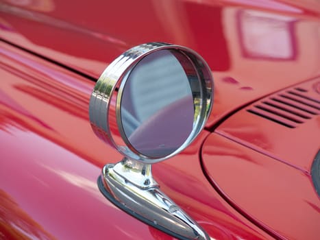 one side mirror on a red car one beutiful thunderbird