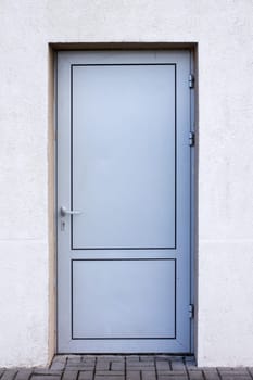 Dirty metallic door in wall of industrial building