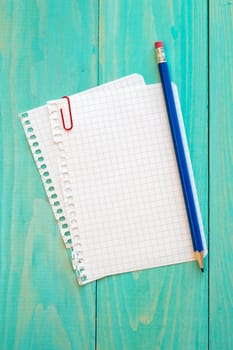 Notebook paper and pencil on the blue surface
