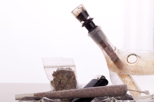 Cannabis marijuana with water pipe and joint with grass and ashtray close-up