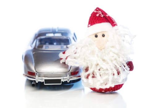 Santa Claus or Father Frost with old vintage automobile on white background with reflection. Main focus of image on Santa Claus and selective on turned the back side toy retro car