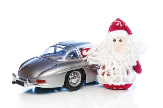 Santa Claus or Father Frost with old vintage automobile on white background with reflection. Main focus of image on Santa Claus and selective on turned the back side toy retro car