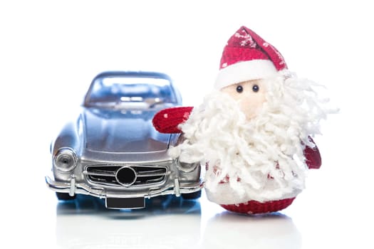Santa Claus or Father Frost with old vintage automobile on white background with reflection. Main focus of image on Santa Claus and selective on face standing toy retro car