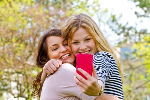 Two girls take a selfie with their mobile phone