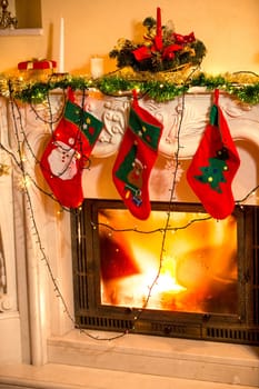 Closeup interior photo of three Christmas stockings hanging on decorated fireplace