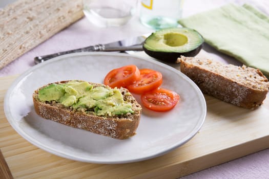 Fresh avocado on thick sliced whole wheat bread with tomatoes.