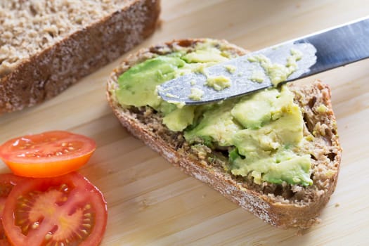 Fresh avocado on thick sliced whole wheat bread with tomatoes.