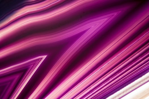 format-filling detail view of a flat,polished and transparent disc of an agate with arrow-shaped structures in violet