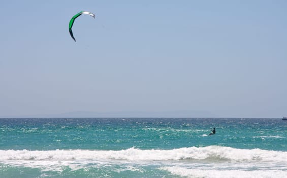 Sportsman kite surfer on clean beach in windy day, Tarifa, Spain