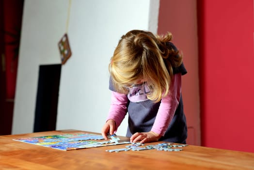 little blond girl doing a jigsaw puzzle