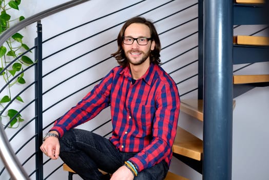 young bearted man in checkered shirt looking friendly in to the camera