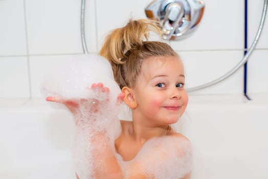 little funny girl with foam bathtub in the bathtub