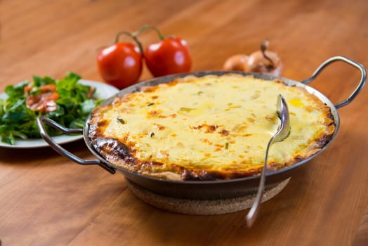 baked quiche with field salad on wooden table