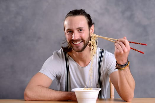 young man eating asian food and smiling in to the camera