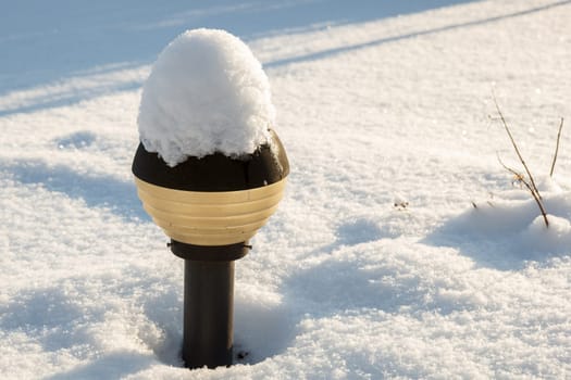 A small lamp post covered with snow