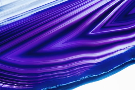 Detailed view of a flat,polished and transparent disc of an agate with arrow-shaped structures in blue against a white background