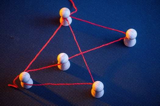 increased detailed view with red thread connected Ludo tiles on dark-puped ground in the side light in red and blue