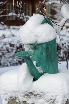 one old watering can on a stone with snow on