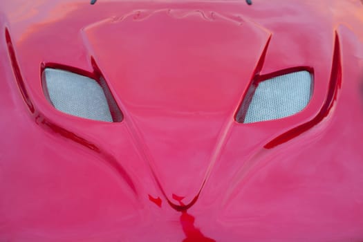 Shiny red car hood with grille shaped as a fox head