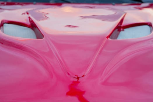 Shiny red car hood with grille shaped as a fox head