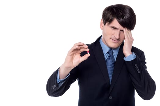 Businessman showing capsule with his hand on forehead