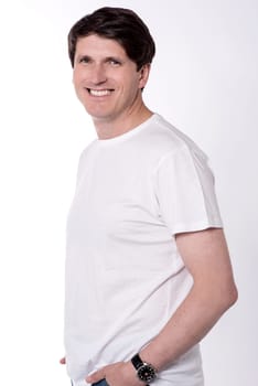 Side pose of happy man with hands in pockets
