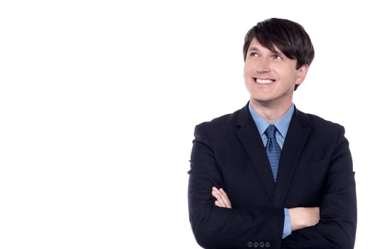 Pensive businessman looking up with folded arms