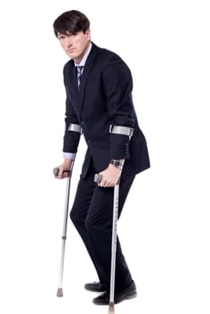 Young businessman posing with his crutches over white