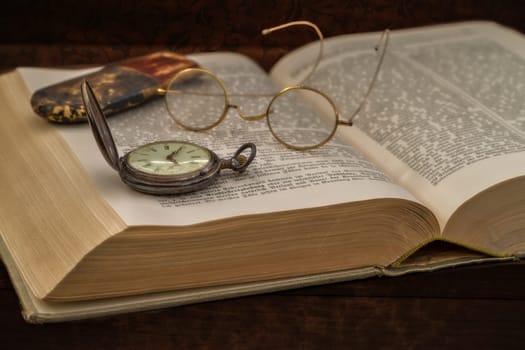 old book with glasses and pocket watch
