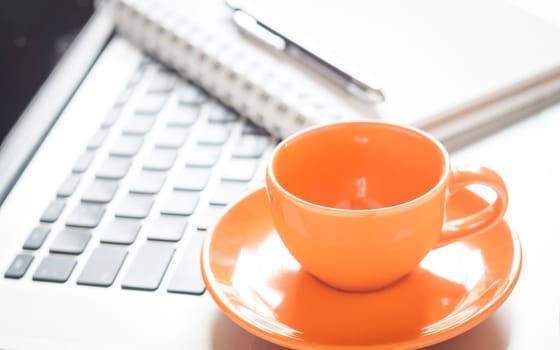 Laptop with coffee cup and notepad on desk, stock photo