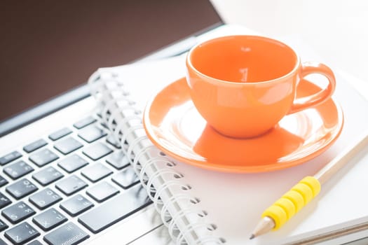 Laptop with coffee cup and notepad on desk, stock photo