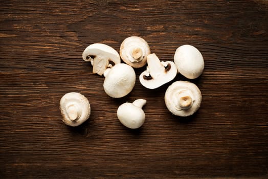 Fresh mushrooms champignons on a wooden background.