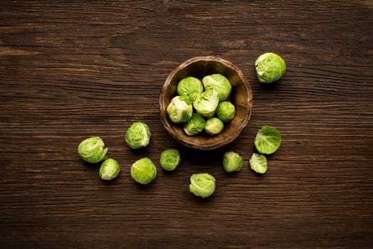 Bunch of fresh Brussels sprouts in a cup on wooden background.
