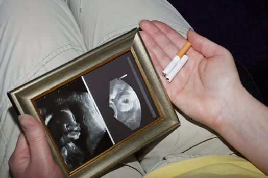 Pregnant woman with ultrasound image and broken cigarette