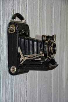 Black old camera hangs on old,white painted wooden wall