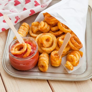 Twisted fries in paper tuete with ketchup