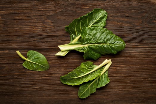 Fresh swiss chard leaves on a wooden background.