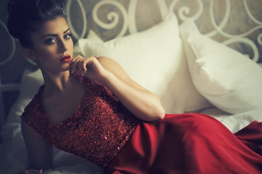Attractive brunette woman lying on sofa in elegant red dress